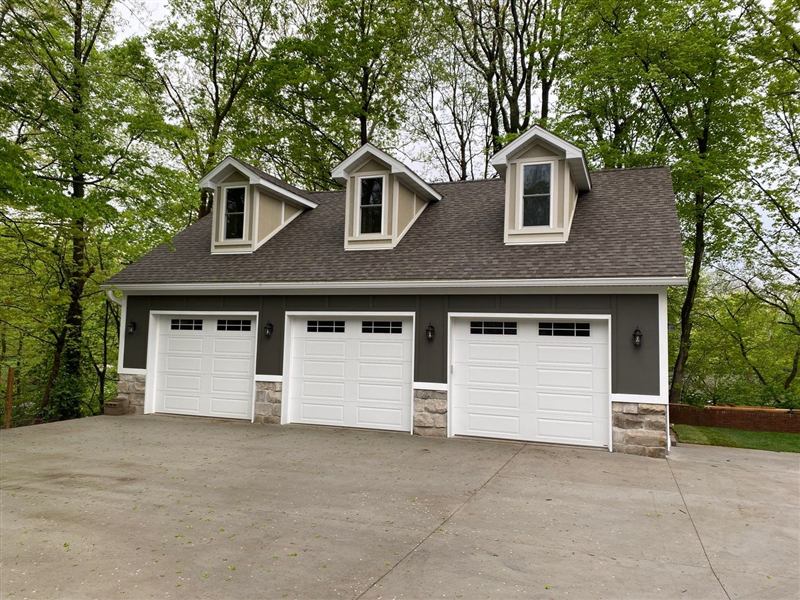 Detached three-bay garage with dormers, carriage doors, and stone wainscoting — new construction in Southwest Illinois