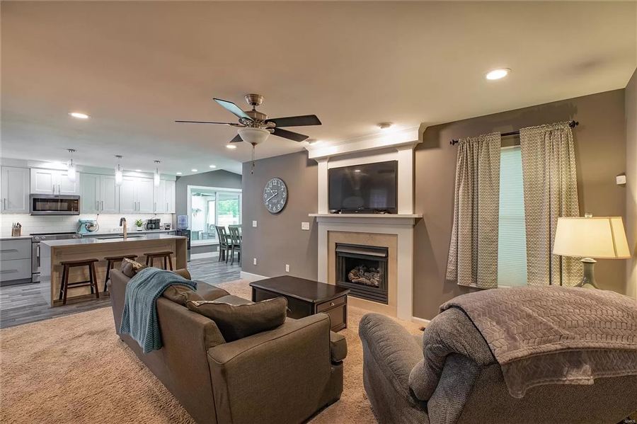 Open living room with fireplace flowing into the remodeled kitchen — Wisteria Drive