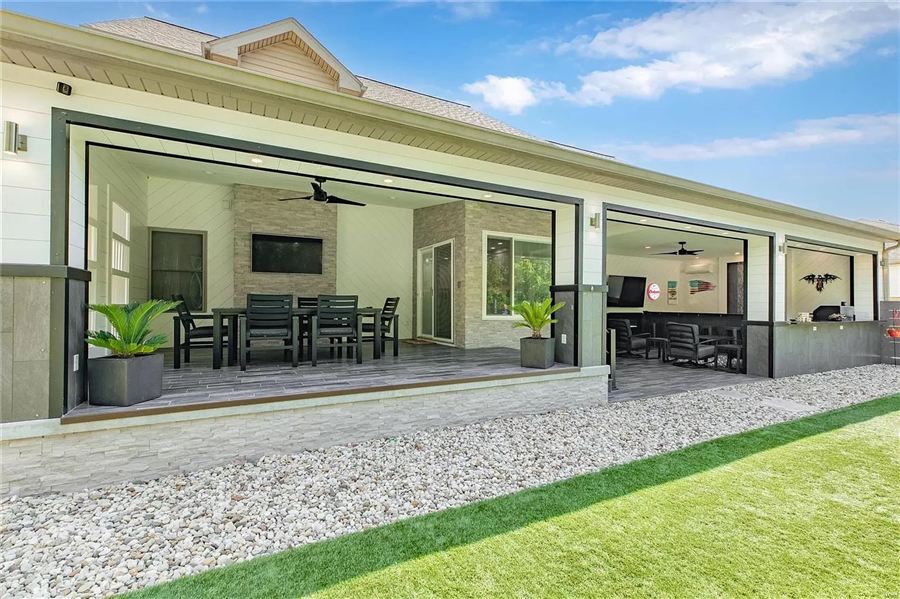 Covered outdoor living room with dining, TV wall, and fireplace — Wisteria Drive